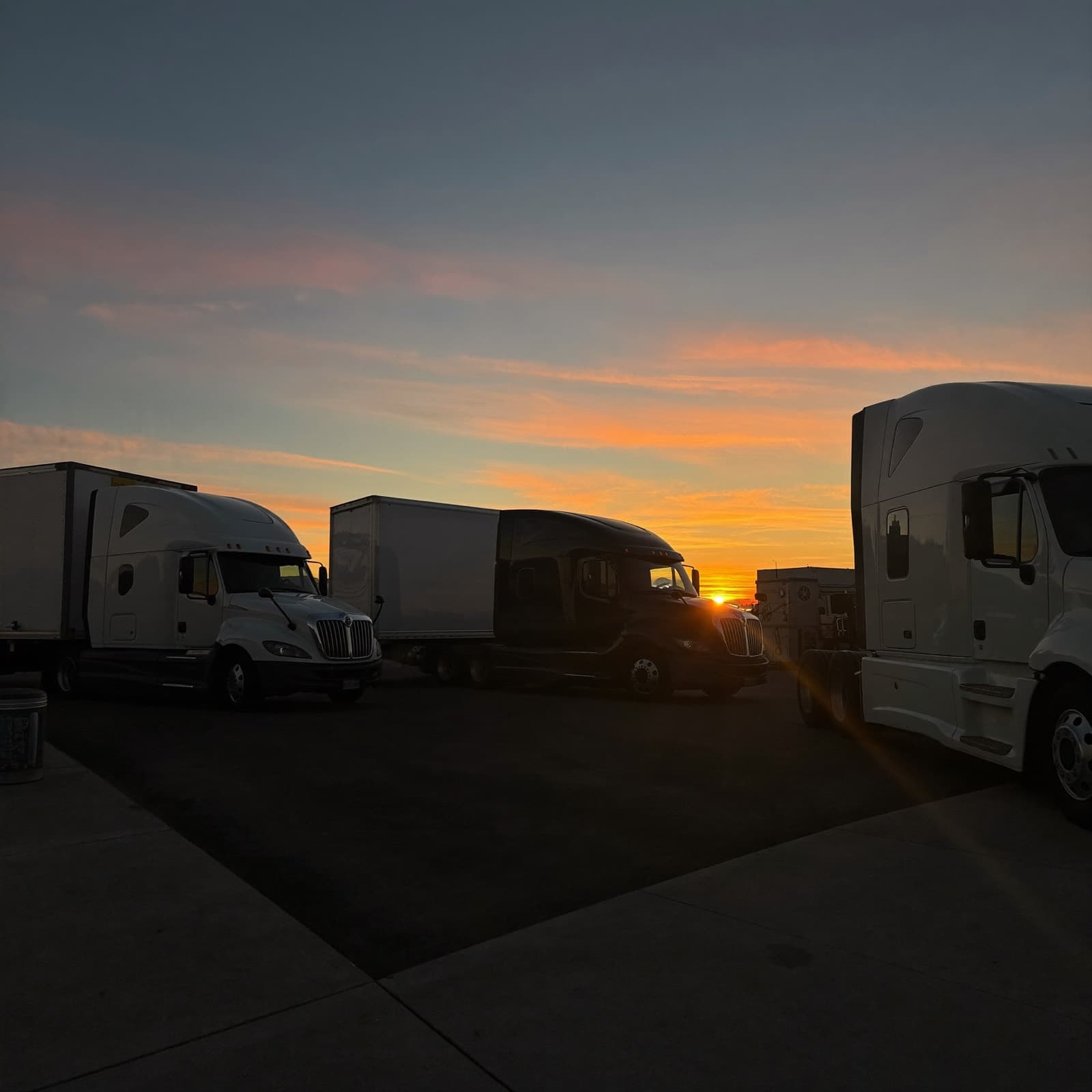 Semi-trucks lined up at a truck stop at golden hour